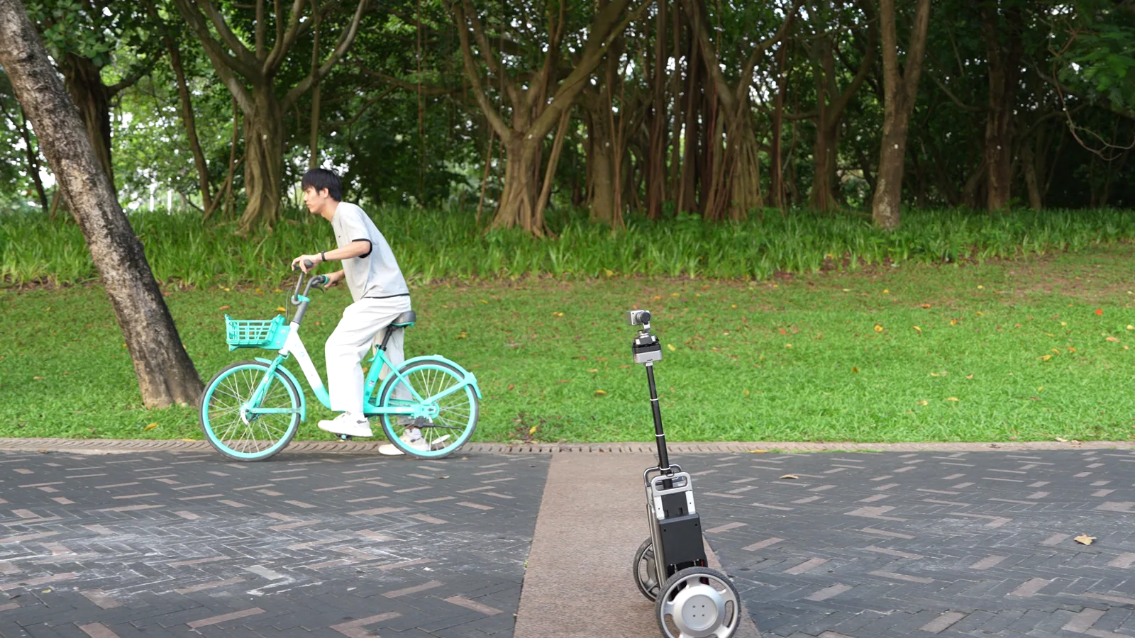 CineyBot moving beside a cyclist on a park path