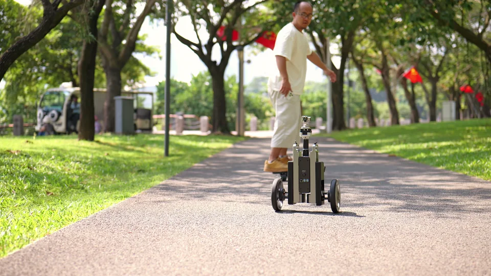 CineyBot following a skater along a tree-lined path